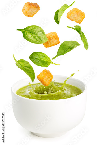 spinach leaves and croutons falling into a soup bowl 