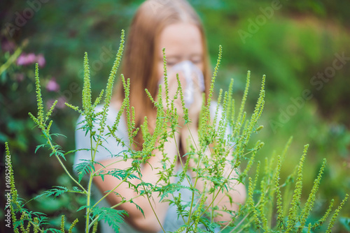 Young woman sneezes because of an allergy to ragweed photo