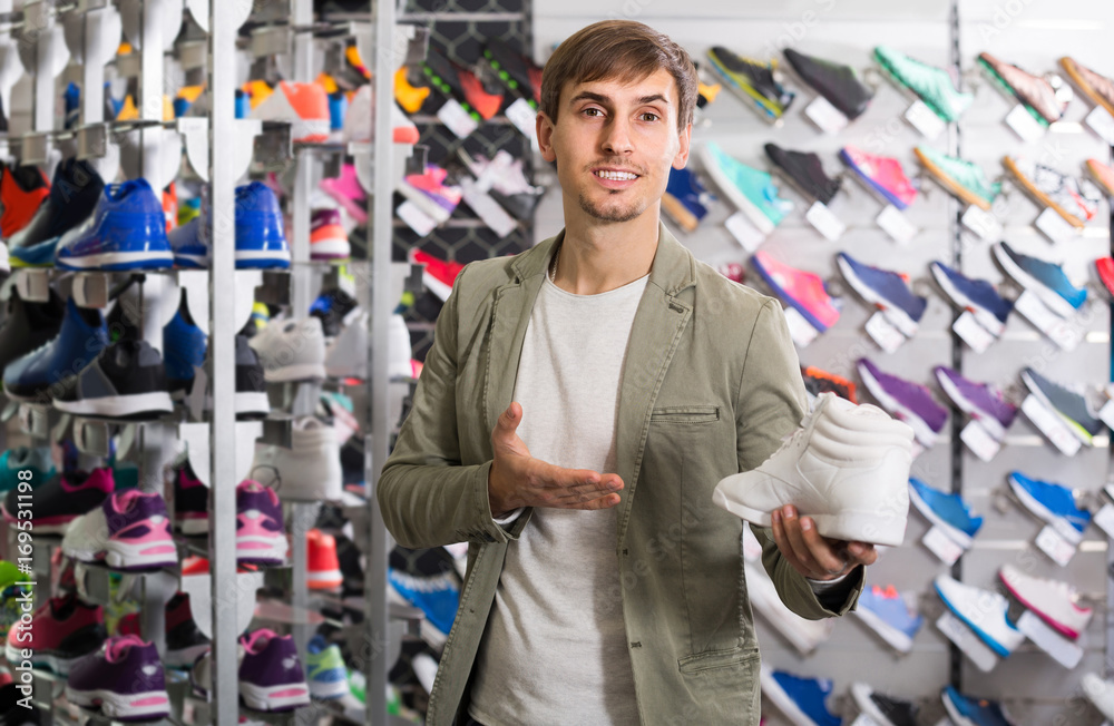 young man showing shoes in the sport store