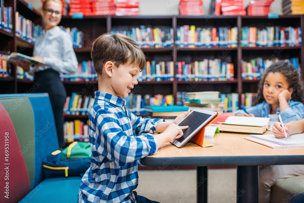 © LIGHTFIELD STUDIOS - schoolboy using tablet at library © LIGHTFIELD STUDIOS - schoolboy using tablet at library