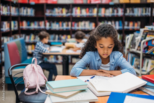 schoolgirl reading book in library