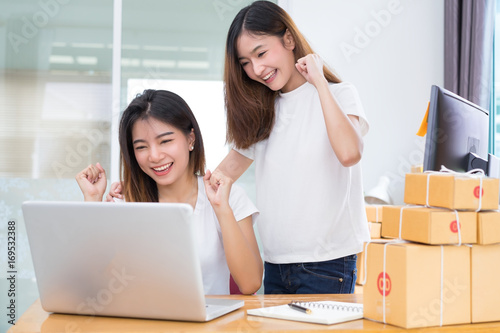 Young asian girl together teamwork freelancer small business private working at home office with laptop, note, phone, packaging delivery online market on purchase checking orders to customer. © Kiattisak