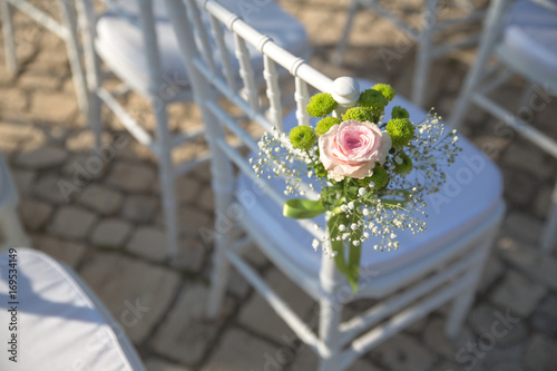 Close up of a floral decoration on a chair made for a wedding ceremony