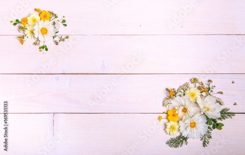 A bouquet of white flowers cosmea or cosmos with ribbon on white boards. Garden yellow flowers over handmade wooden table background. Backdrop with copy space. © Olga Ionina