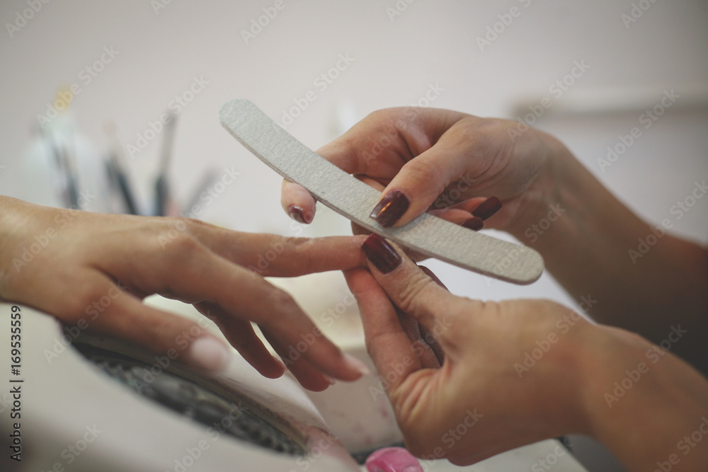 Close-up of female hands being manicured at a beauty salon.