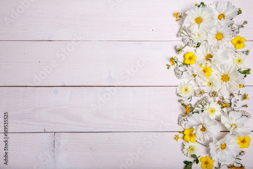 A bouquet of white flowers cosmea or cosmos with ribbon on white boards. Garden yellow flowers over handmade wooden table background. Backdrop with copy space. © Olga Ionina