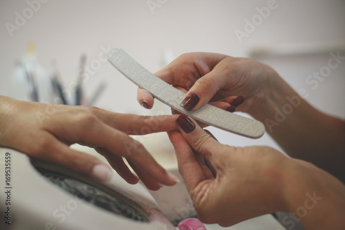 Close-up of female hands being manicured at a beauty salon.