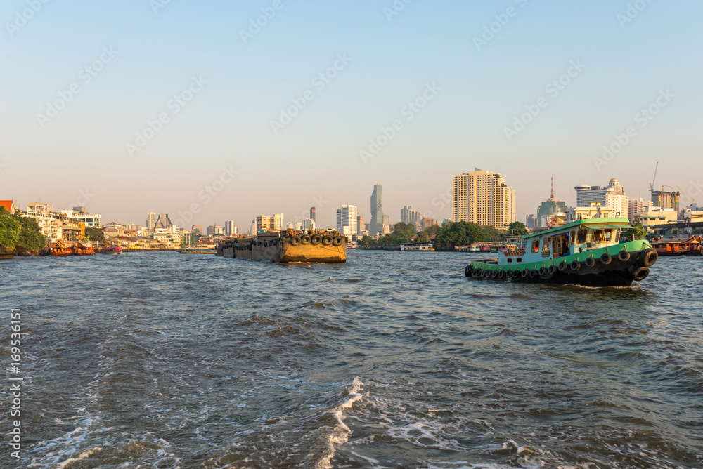 Pusher with barges on the Chao Phraya river in Bangkok. The river meanders through the city in southward direction, emptying into the Gulf of Thailand approx 25 kilometres south of the city centre