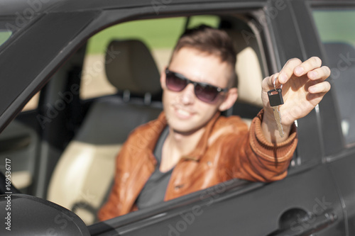 Young man in car showing keys