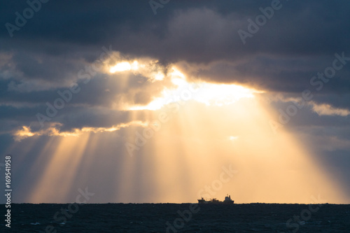 雲間から差し込む光、海と1隻の船