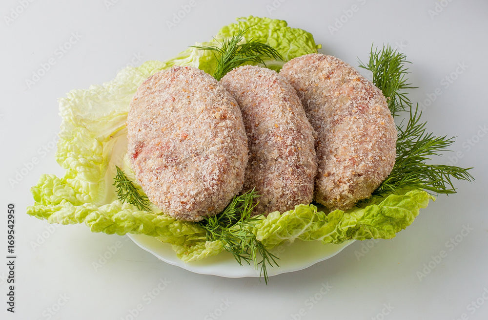 Raw semifinished cutlet with greens on a plate. Isolated Raw semifinished cutlet with greens on a plate. Isolated