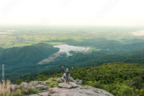 Young man enjoying a valley view from top of a mountain.