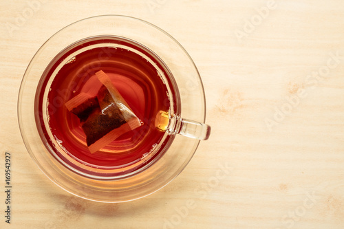 A cup of tea on the wooden table, tea bag in glass.