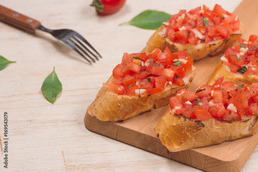 Italian bruschetta with roasted tomatoes, mozzarella cheese and herbs on a cutting board