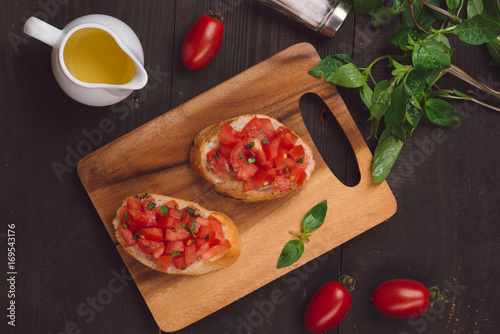 Simple italian appetizing bruschetta with tomato, on wooden table