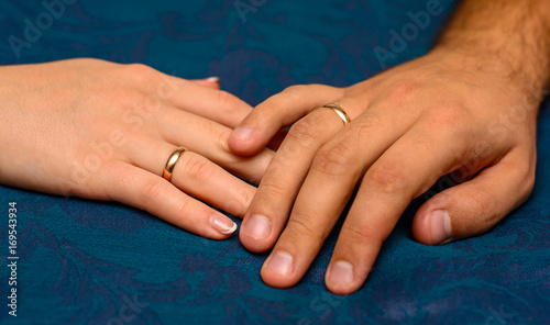 Photo of hands with beautiful wedding rings on blue background