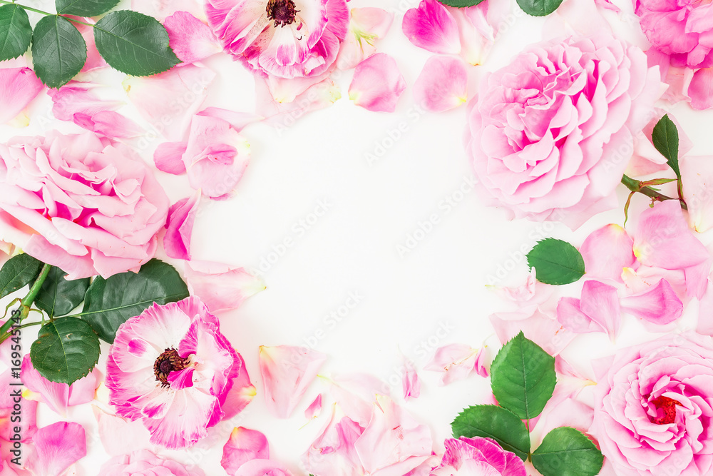 Round wreath frame of roses, pink flowers and leaves on white background. Flat lay, top view.
