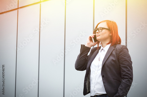 Business concept of success, telephone conversations. Serious Successful Woman boss, in suit, glasses with phone, emotionally demonstrates achievement. place for advertising text. Chef Day Boss Day photo