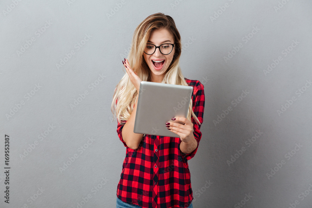 Surprised young blonde woman chatting by tablet computer. Surprised young blonde woman chatting by tablet computer.