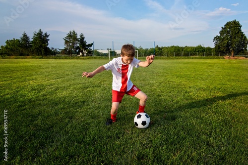 Boy playing with football ball on playing field.