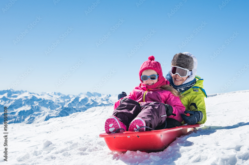 Children sledding on snow - obrazy, fototapety, plakaty 
