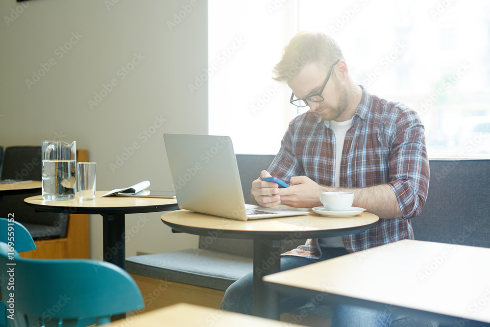 Young hipster businessman or designer texting in cafe Young hipster businessman or designer texting in cafe
