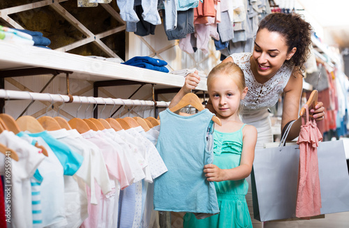 portrait of woman and girl shopping kids apparel in clothes store