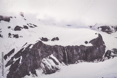 Snow covered ridge with small stream cascading over cliff