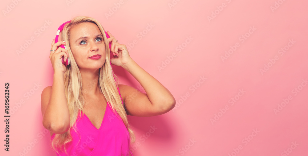 Happy young woman with headphones on a pink background Happy young woman with headphones on a pink background
