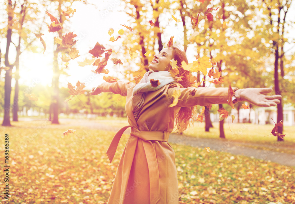 happy woman having fun with leaves in autumn park