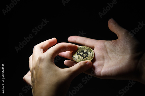 woman's hand holding golden Bitcoin on black background photo