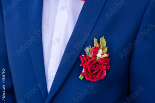 Red boutonniere on a blue suit.