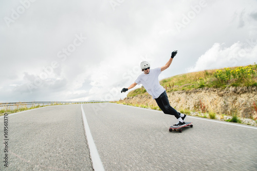 A young man performs a complicated stunt on a longboard