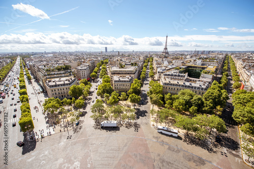 Aerial wide angle cityscape view on the beautiful buildings and avenues with Eiffel tower on the background during the sunny day in Paris