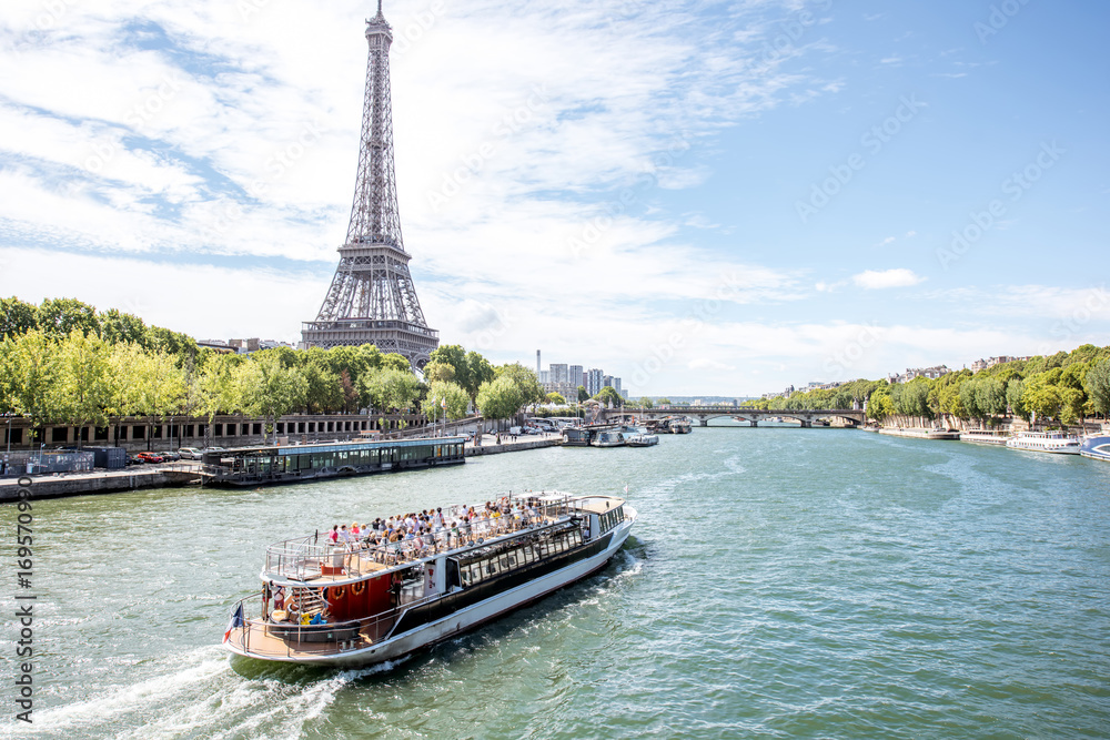 Obraz premium Landscpae widok na wieży eifla i wonton rzece z turystyczną łodzią w Paryż