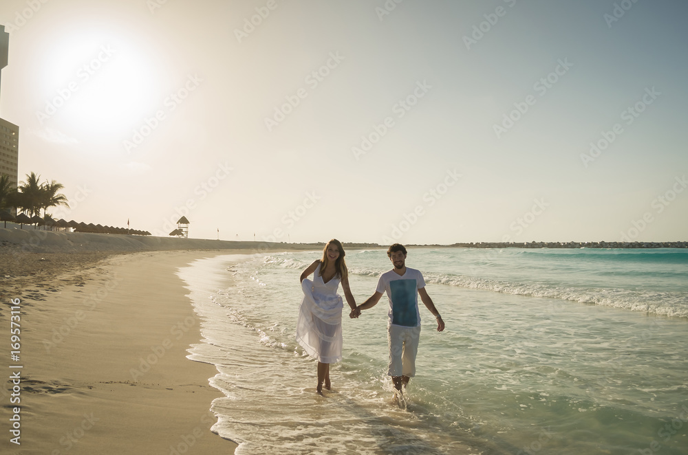 Casal de namorados caminhando na praia de mãos dadas, de frente, mar do caribe no pôr-do-sol Casal de namorados caminhando na praia de mãos dadas, de frente, mar do caribe no pôr-do-sol