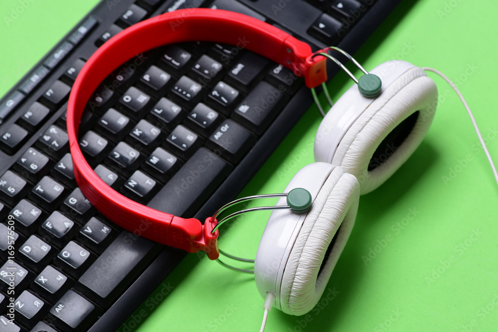 Headphones and black keyboard. Earphones in red and white colors Headphones and black keyboard. Earphones in red and white colors