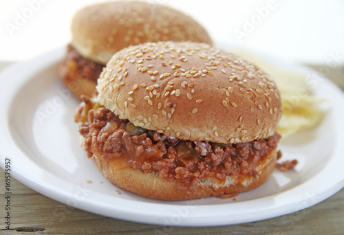 Fotografie Two sloppy joe sandwiches on sesame seed buns with potato chips and room for tex
