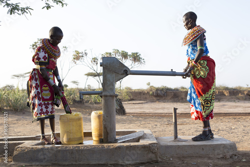 Samburu tribal women collecting fresh water from well in desert landscape. Kenya, Africa. photo
