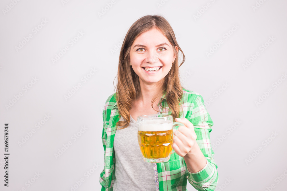 Cheerful young woman holding a beer mug full of beer and smiling on white background Cheerful young woman holding a beer mug full of beer and smiling on white background