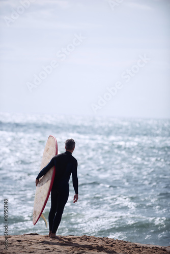 On the beach. Surfer silhouette of a man holding his surf board