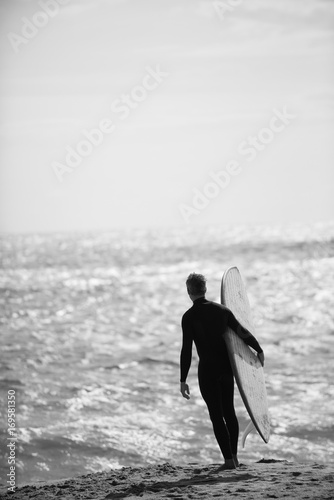 On the beach. Surfer silhouette of a man holding his surf board