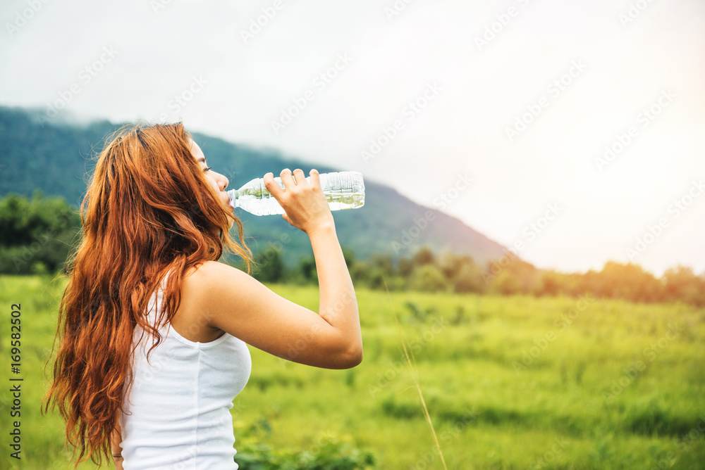 Asian women travel relax in the holiday. Drink Water on a green pasture. Asian women travel relax in the holiday. Drink Water on a green pasture.