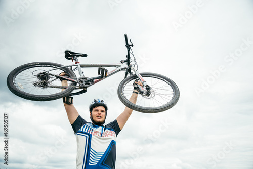 man holdin his bike under his had photo