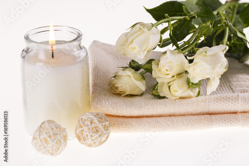 Spa. Burning candle  white roses and a towel on a white background