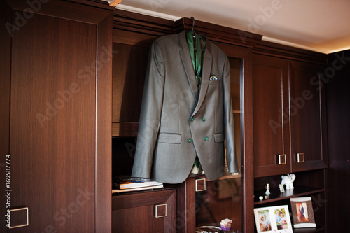 Groom's wedding tuxedo hanging on the rack on the wardrobe.