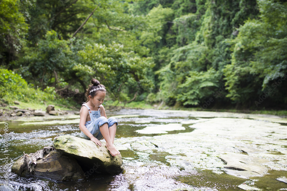 Fototapeta premium Little girl playing in the mountain stream