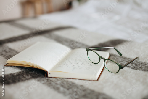 Glasses and journal on a bed