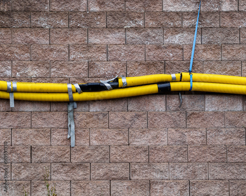Yellow drainage pipes held together with tape on a brick wall
