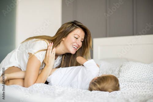 Mother playing with little boy on bed